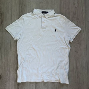 Vit pikétröja från Polo Ralph Lauren - Klassisk vit pikétröja från Polo Ralph Lauren med korta ärmar och broderad logga på bröstet. Den är storlek L men sitter som M/L. Hör av er vid frågor. Passade bra när jag va 179, säljer pga att den är för liten nu. Pris kan diskuteras 