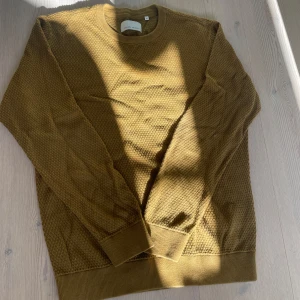 Brun stickad tröja Casual Friday - Säljer en brun stickad tröja från Casual Friday i storlek M. Tröjan har en snygg strukturstickning, rund halsringning och ribbade muddar vid ärmslut och nederkant. Perfekt för lager-på-lager under hösten och vintern. Skicket är riktigt bra