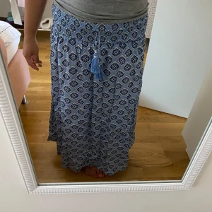 Blå långkjol från Gina Tricot - Supersnygg blå långkjol från Gina Tricot med vitt och mörkblått blommönster. Kjolen har smock i midjan och är stretchig! Kjolen är använd och tvättad❣️💛 