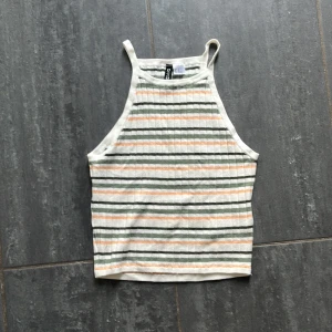 Randig ribbad linnetopp från H&M Divided - Säljer en ribbad linnetopp från H&M Divided i storlek XS. Toppen är vit med gröna och orangea horisontella ränder, har smala axelband och croppad passform. 