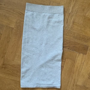 Ljusgrå ribbad kjol från Aim'n XS - Supersnygg ljusgrå ribbad kjol från Aim'n i midilängd. Kjolen är figurnära och har en bred, elastisk midja med en liten metallbricka med Aim'n-logga framtill. Materialet är mjukt och stretchigt, perfekt för en chill och sportig look.