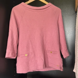 Hampton republic rosa trekvartsärmad topp - Säljer en rosa tröja med snygg struktur och trekvartsärm. Tröjan har två dekorativa detaljfickor framtill med guldknappar som detalj. Perfekt för dig som gillar en chill men ändå stilren look.