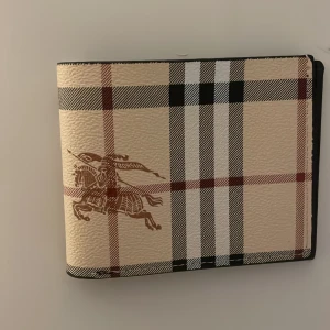 Burberry plånbok - Clean plånbok från burberry. Säljer för 750kr den kostade 1200kr ny, helt nytt skick, jag har knappt använt den då jag tyckte den va lite för stor.