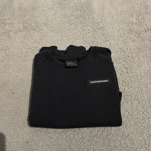 Svart Peak Performance sweatshirt - Svart sweatshirt från Peak Performance med broderad logga på bröstet. Klassisk rund halsringning, ribbade muddar och lång ärm. Perfekt basic-tröja i mjuk bomull som funkar till allt. Storlek 160.