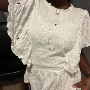 Vit broderad blus med volang - Superfin vit blus med broderade detaljer och volangiga ärmar. Toppen är knappt använd och säljs då den inte inte kommer till användning 