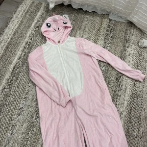 Rosa enhörnings onepiece från H&M Divided - Supermysig rosa onepiece i enhörningsstil från H&M Divided. Tröjan har huva med ansikte, horn och regnbågsfärgad man, samt dragkedja framtill. 