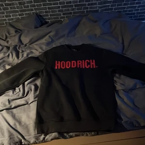 Svart Hoodrich Tröja - Svart tröja från Hoodrich med röd logga. Klassisk rund halsringning och långa ärmar. 