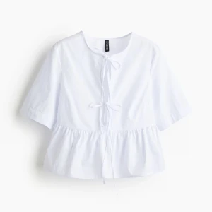 Vit blus med knyt från hm - Supersöt vit blus från Divided med knyt framtill och lätt volang nedtill. Blusen har korta ärmar och en luftig passform som ger en chill vibe. Perfekt till jeans eller kjol för en fräsch look.