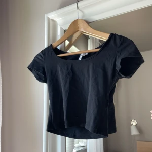 Svart croppad topp från H&M Divided - Enkel svart croppad topp från H&M Divided med rund halsringning och korta ärmar. Tillverkad i mjuk bomull, perfekt till jeans eller kjol. Snygg basic som funkar året runt och är lätt att matcha med andra plagg. Ser väldigt kort ut på bild men de är meningen, den är stretchig💗 pris går att diskutera, skriv för fler bilder💗
