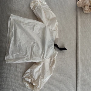 Vit blus med puffärm och svart knyt - Vit blus med stora puffärmar och svart knytband i ryggen. 