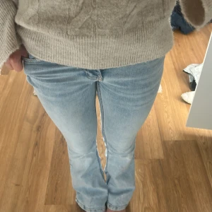 Ljusblå bootcut jeans - Säljer ett par ljusblå jeans med bootcut-modell och klassisk femficksdesign. Jeansen har låg midja och är tillverkade i mjukt denimtyg som sitter snyggt över höfterna och låren. De är lite slitna nere vid hälen