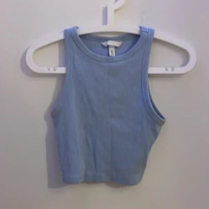 Ljusblå ribbad linnetopp H&M S - En ljusblå croppad linnetopp från H&M i ribbad bomull. Toppen är ärmlös med hög halsringning och har en tight passform som sitter snyggt. Pris kan diskuteras :)