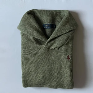 Olivgrön stickad tröja Polo Ralph Lauren - Säljer en olivgrön stickad tröja från Polo Ralph Lauren i storlek S/M. Tröjan har en bred krage och långärmade ribbade muddar. Klassisk broderad logga i vinrött på bröstet. Perfekt för dig som gillar stilrena och tidlösa plagg. Skicket är som på bilden, lite knopprig kanske. Inga hål eller missfärgningar. Inte en hoodie.