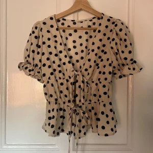 Prickig blus med knyt detaljer  - V-ringad prickig jättesöt blus/topp som man knyter framtill. Köpt från en på vinted så vet tyvärr inte vart den är köpt. Storlek står inte heller men skulle gissa på S/M men storleken går att reglera lite med hjälp av knyt banden.
