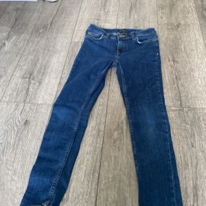 Blå skinny jeans XOXO - Säljer ett par klassiska blå skinny jeans från Levis med fem fickor och knappgylf. Jeansen har en smal passform och raka ben, perfekt för dig som gillar en clean och tidlös look. Materialet är slitstarkt jeans och färgen är mörkblå. 