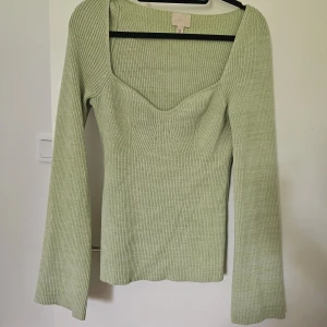 Ljusgrön ribbad tröja från H&M - Supersnygg ljusgrön ribbad topp från H&M med lång ärm och markerad byst. Toppen har en fyrkantig urringning och är figurnära i modellen. Knappt använd, så väldigt fint skick 