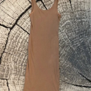 Beige ribbad långklänning från SHEIN,xs  - Snygg beige långklänning från SHEIN med ribbad struktur och ärmlös design. Klänningen har en rundad halsringning och figurnära passform som framhäver siluetten. Perfekt för dig som gillar stilrena och enkla plagg med lite edge.