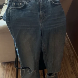 Blå bootcut jeans från Pull&Bear - Säljer ett par blå bootcut jeans från Pull&Bear i storlek 36. Jeansen har slitna detaljer och hål vid knäna för en cool, avslappnad vibe. Klassisk femficksmodell med hög midja och dragkedja. Perfekta till sneakers eller boots.