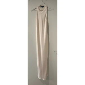 Glansig midiklänning med öppenrygg Zara - Säljer en elegant och stilren långklänning från Zara i champagnefärgad ton. Klänningen är ärmlös med hög hals och har en snygg öppen rygg med tvistat tyg. Materialet är mjukt och har ett lätt satinliknande fall som ger en lyxig känsla. Endast använd 2 gånger, men finns lite tecken på användning. Storlek XS men skulle säga att den passar både S och M också!