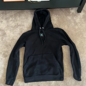 Svart hoodie ( The cool Elephant ) - Svart hoodie men stor ficka och luva. På ryggen är en bild med olika färger. Tröjan är köpt på ” the cool elephant” Använd ett par gånger men i stort sett inte använd.