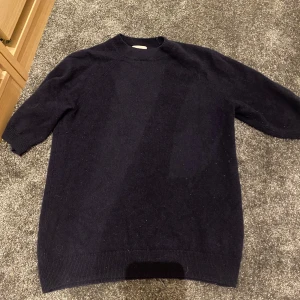 Mörkblå kashmirtröja från H&M XS - Snygg mörkblå tröja i mjuk kashmir från H&M. Modellen har halvlånga ärmar och en klassisk rund halsringning. Perfekt för dig som gillar stilrena och bekväma plagg med lyxig känsla.