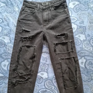 Svarta jeans med slitningar - Ett par svarta snygga jeans med slitningar framtill. Har bara blivit liggandes i garderoben. 