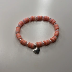Rosa armband med hjärthänge - Supergulligt handgjort armband med platta rosa pärlor samt runda vita, och ett silvrigt hjärthänge. Perfekt accessoar för att ge din outfit en söt och gullig touch. Bara att fråga om mått💕