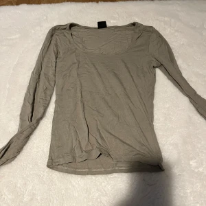 Grön långärmad topp med rund hals - Snygg grön långärmad topp med rundad halsringning. Tillverkad i mjuk bomull som känns skön mot huden. Passar perfekt till jeans eller kjol och har en enkel, clean look utan mönster eller detaljer. Perfekt för dig som gillar basic och stilrent.