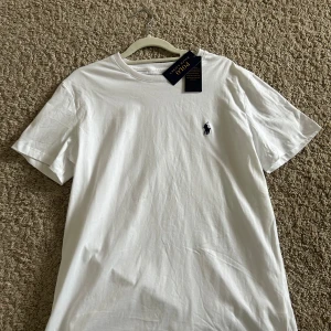 Vit t-shirt Polo Ralph Lauren slim fit man - Vit t-shirt från Polo Ralph Lauren i slim fit-modell. Klassisk design med korta ärmar och rund hals. Diskret broderad logga på bröstet. Tillverkad i mjuk bomull som känns skön mot huden. Perfekt för dig som gillar stilrena och tidlösa plagg.
