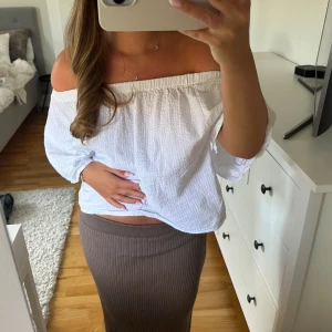 Brun ribbad långkjol - Säljer en snygg brun ribbad långkjol med stretchig midja. Kjolen har en rak och smickrande passform som sitter bekvämt och följer kroppen. Perfekt att matcha med en off shoulder-top eller en stickad tröja för en chill look.