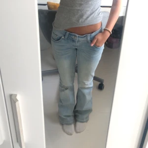 Low Waist Bootcut Jeans - Tänkte kolla intresset på dessa ljusblåa lågmidjade bootcut jeansen från G-rise i strl. S, short length. Skitsnygga, designat med hål på vänster knä!! Defekter på sista bilden där det är slitage vid hälarna samt fläckar från regniga dagar som inte går bort, men bortsett från det är jeansen i ”Mycket bra skick”. De säljs inte längre på hemsidan.