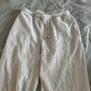 Grå mjukisbyxor med snörning - Säljer ett par grå mjukisbyxor med elastisk midja och snörning. Byxorna är i mjukt material och har en avslappnad passform, perfekta för chill dagar eller när du vill vara bekväm. Enkla att matcha med hoodie eller t-shirt. Lågmidjade! 
