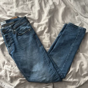 Slim fit jeans från Jack & Jones - Blå slim fit jeans från Jack & Jones, modell Glenn. Klassisk femficksdesign med snygga kontrastsömmar och läderpatch bak i midjan. Jeansen har en smal passform och är tillverkade i mjukt denimtyg för en bekväm känsla.