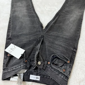 Svarta jeans från Zara, straight fit - Snygga svarta jeans från Zara i straight fit-modell. Jeansen har klassisk femficksdesign, dragkedja och knapp i midjan samt coolt tvättad look. Perfekta till sneakers eller boots för en avslappnad stil.