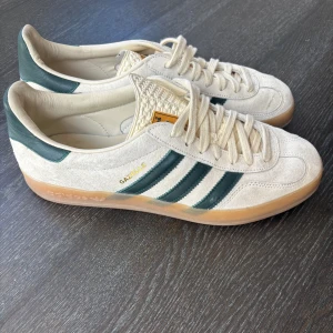 Adidas Gazelle sneakers i mocka - Hej, säljer mina  Adidas Gazelle sneakers i beige mocka med mörkgröna detaljer, säljer dem då dem inte kommer till så mycket användning som jag vill längre. Dem är i mycket bra skick, nypris 1700kr. Har köpbevis från bankkonto men dem är köpte i USA där jag bor så tog inte med kartongen eller något från StockX(där dem är köpta) EU storlek: 43