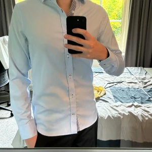 Ljusblå slim fit skjorta från Riley - Hej, Säljer en ljusblå skjorta från Riley i slim fit-modell i storleken S. Skjortan har långa ärmar, klassisk krage och knappar framtill. Insidan av kragen har ett snyggt rutigt mönster i blått och vitt. Hör av dig vid frågor eller funderingar!😁