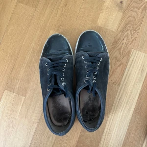 Lanvin - Svarta sneakers från Lanvin med ovandel i mocka och detaljer i skinn. Skorna har rund tå, svarta snören och vit sula. Klassisk och stilren design med diskret logga på sulan. Perfekta för dig som gillar lyxiga och tidlösa sneakers. Inte jätte bra skick, priset går att diskutera, hör av dig vid minsta fundering!