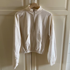 Beige half zip sweatshirt Missguided - Beige sweatshirt från Missguided med half zip och hög krage. Tröjan har lång ärm, elastisk midja och en stor ficka framtill. Storlek 36. Helt okej i skicket, mycket använd. Lite ytnopprig, men fortfarande användbar. Kort modell. 