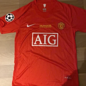 Manchester United Finaltröja Ronaldo 2008 - Manchester Uniteds officiella finaltröja från Champions League-finalen 2008 i Moskva. Röd med gula detaljer, AIG-logga, klubbmärke och Nike-swoosh framtill. På ryggen står det Ronaldo och nummer 7. Tillverkad i ventilerande polyester.