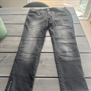 Svarta skinny jeans med dragkedjor - Snygga svarta skinny jeans med slitningar och dragkedjor vid fickorna framtill. Byxorna har även dragkedja vid benslut och markerade sömmar över knäna för en cool look. Perfekta för dig som gillar en lite tuffare stil.