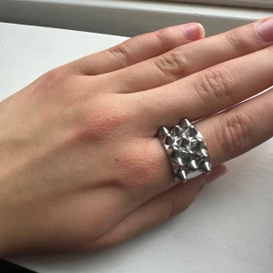 Silvrig ring med nitar från Edblad - Cool och chunky ring från Edblad i silverfärgad metall. Ringen har en bred design med flera konformade nitar på ovansidan som ger en edgy och unik look. Knappt använd eftersom den är för stor. Pris kan diskuteras.