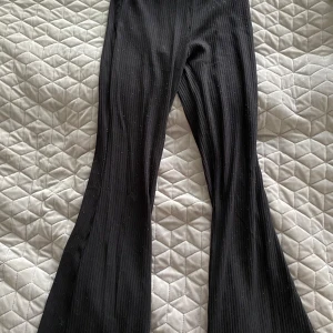Svarta ribbade bootcut-byxor H&M - Svarta ribbade byxor från H&M i storlek 158. Byxorna har bootcut-modell med utsvängda ben och är tillverkade i ett stretchigt, mjukt material. Perfekta för en chill och trendig look.