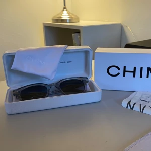 Grå transparenta solglasögon från CHIMI - Snygga solglasögon från CHIMI med transparent grå båge och mörka linser. Modellen har en klassisk, rundad fyrkantig form och levereras med originaletui och oöppnad putsduk,original box samt även original kvitto från när jag köpte de. Glasögona är Perfekta inför sommaren! Modellen är Chimi 02M Grey och jag köpte de för 1200kr. Jag har inte alls använt de något särskilt och därav det näst intill oanvända skicket! Jag säljer de därför för 800kr!! Om fler bilder önskas så skriv:)