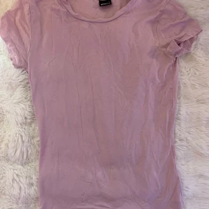 Ljus rosa t-shirt från Gina Tricot - En basic rosa t-shirt från Gina Tricot i storlek S. Modellen är klassisk med rund halsringning och korta ärmar. Perfekt att matcha med jeans eller kjol för en chill look. Bara använd ett fåtal gånger med bara några små defekter, men de ser man inte när man har på sig den. 