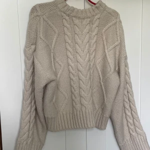 Beige kabelstickad tröja - Säljer en chunky beige stickad tröja med grovt kabelstickat mönster och ribbade muddar. Tröjan har en lite loose passform och lång ärm💕💕ej nopprig