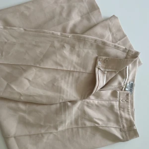 madlady beiga kostymbyxor  - jättefina beiga kostymbyxor ifrån madlady. väldigt stretchiga i materialet och fina detaljer, ser lite skrynkliga ut då dem bara legat i garderoben. storleken är 32/xxs men passade mig fint som har 32-36/xs-m. endast använd några gånger och normala i storleken. en liten skavank på baksidan där sömmen gått upp lite grann, men syns ej på, syns på sista bilden. pris går att diskuteras!!