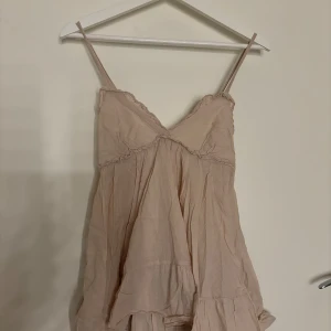 Beige topp - Supersöt beige linnetopp med tunna axelband och volangig nederkant. Toppen har v-ringning och små volangdetaljer längs kanterna. Finns ingen lapp i men skulle säga att den passar 36 och uppåt💕💕
