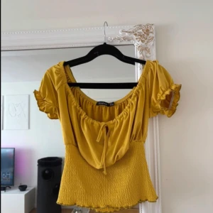 Gul blus med volang från Boohoo - Super fin och söt gul blus från Boohoo med korta puffärmar och volangdetaljer. 