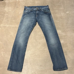 Blå Lee Gold Label jeans straight fit 101Z - Snygga blå jeans från Lee Gold Label med klassisk femficksdesign, zipgylf och raka ben. Jeansen har en mellanblå tvätt med lätt slitning och Lee-logga på bakfickan samt läderpatch i midjan. Perfekta för en avslappnad och stilren look. 100% bomull!