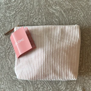 Rosa ribbad necessär från Lancôme - Supersöt necessär från Lancôme i ljusrosa manchester med ribbad struktur och dragkedja. Innehåller , toner, mascara, serum , dag & nattkräm🎀